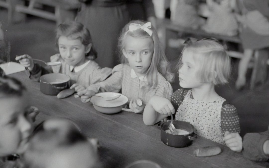 Three young girls at a table eating and are at risk for eating disorders.