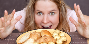 a woman's face as she approaches a plateful of highly palatable foods, suggesting she hears food noise as a trigger.