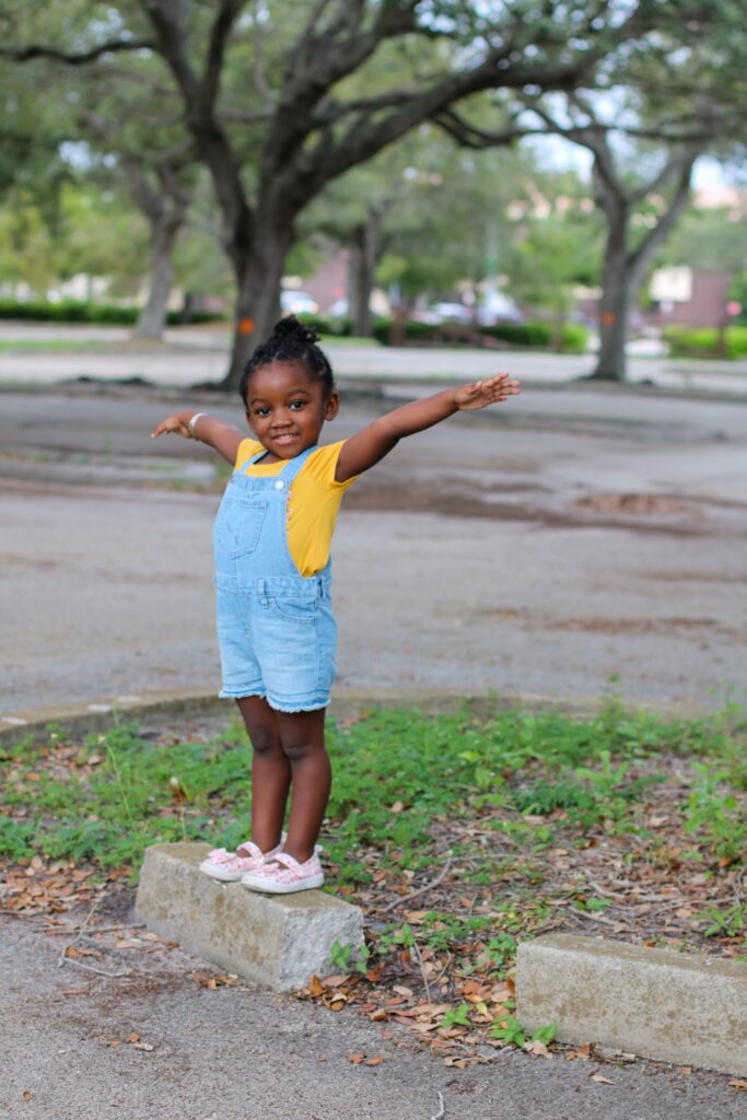 A child standing on a rick with her arms outstretched, demonstrating her superpowers as a Highly Sensitive Person