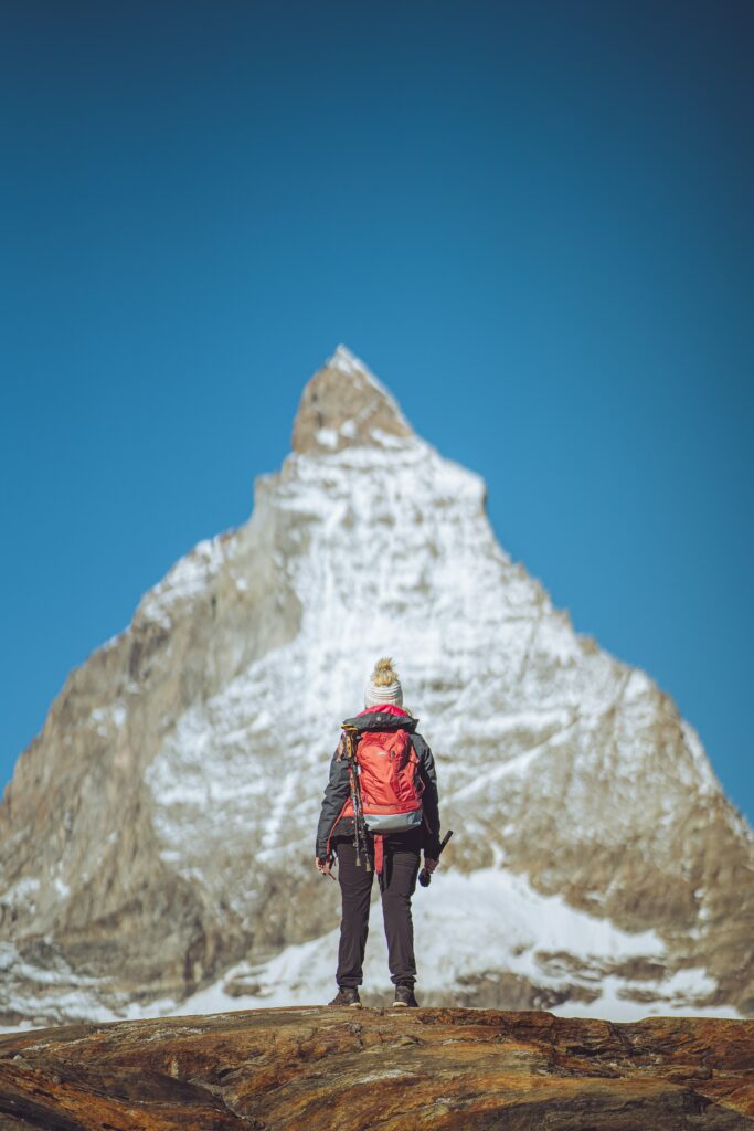 a woman standnig in front of a tall snow covered mountain