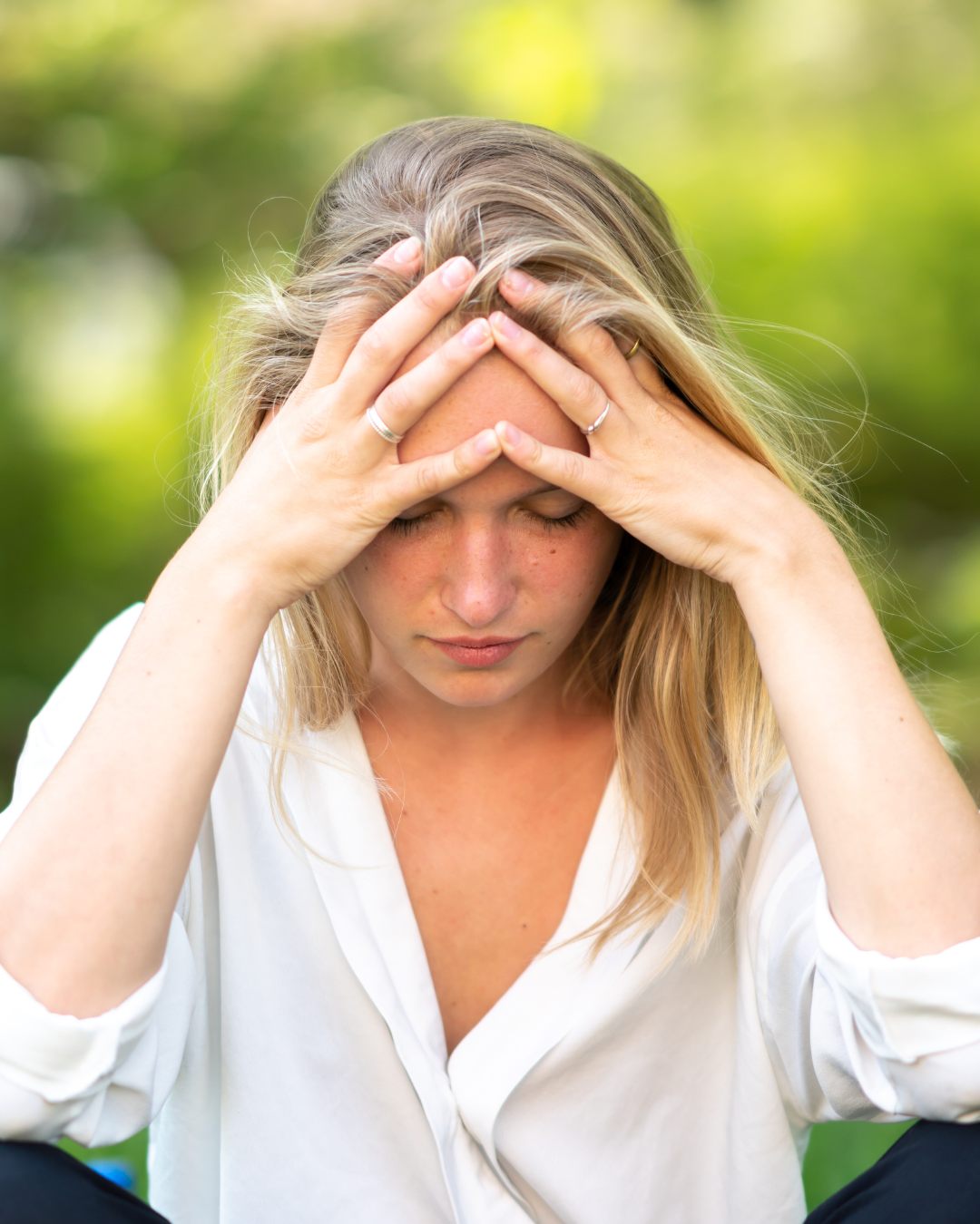 A young blonde woman with her head in her hands, appearing sad or anxious